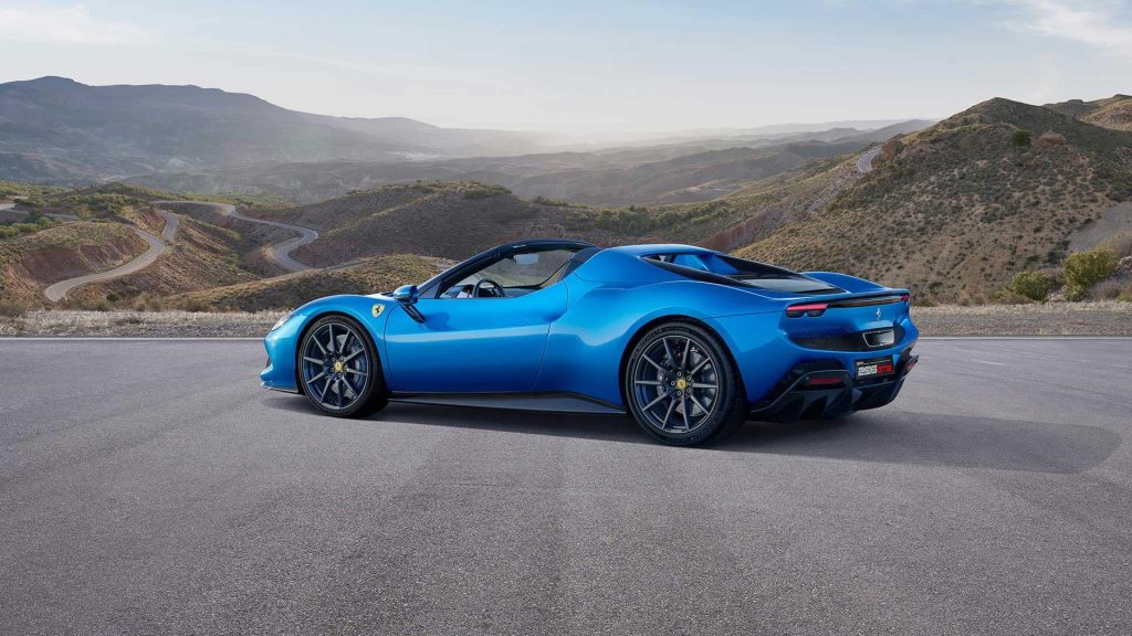 A blue Ferrari 296 GTS in front of a mountainous road