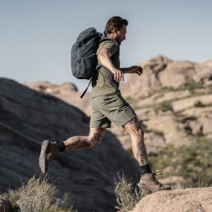 A man is jumping over large rocks wearing a pair of Ten Thousand's Tactical Utility Shorts